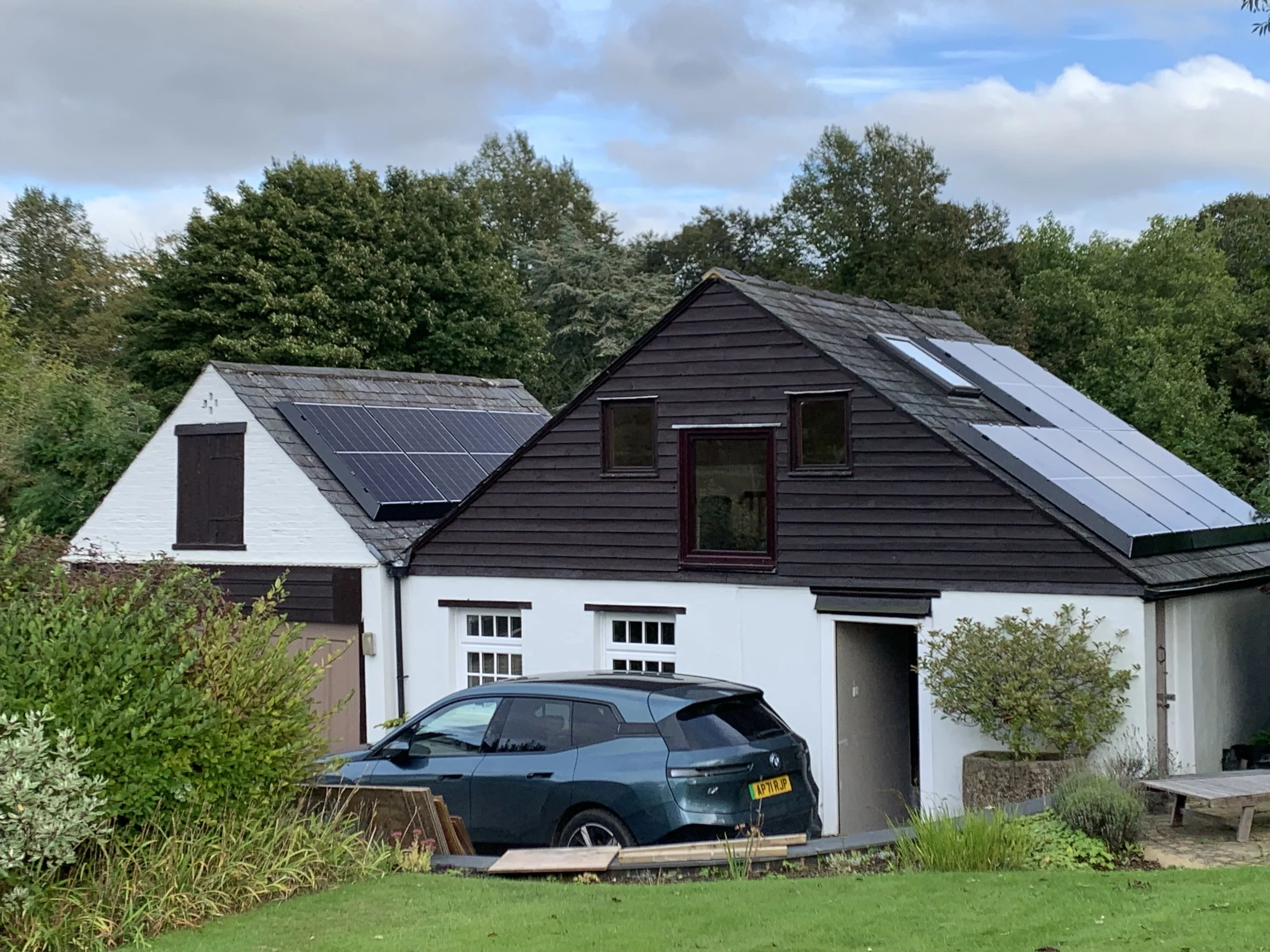 Residential home with solar panels on multiple roofs, car in front